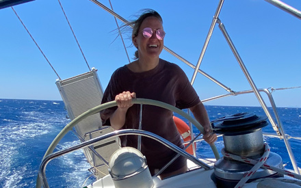 Frau steht bei Segeltörn in Italien am Steuer der Segelyacht